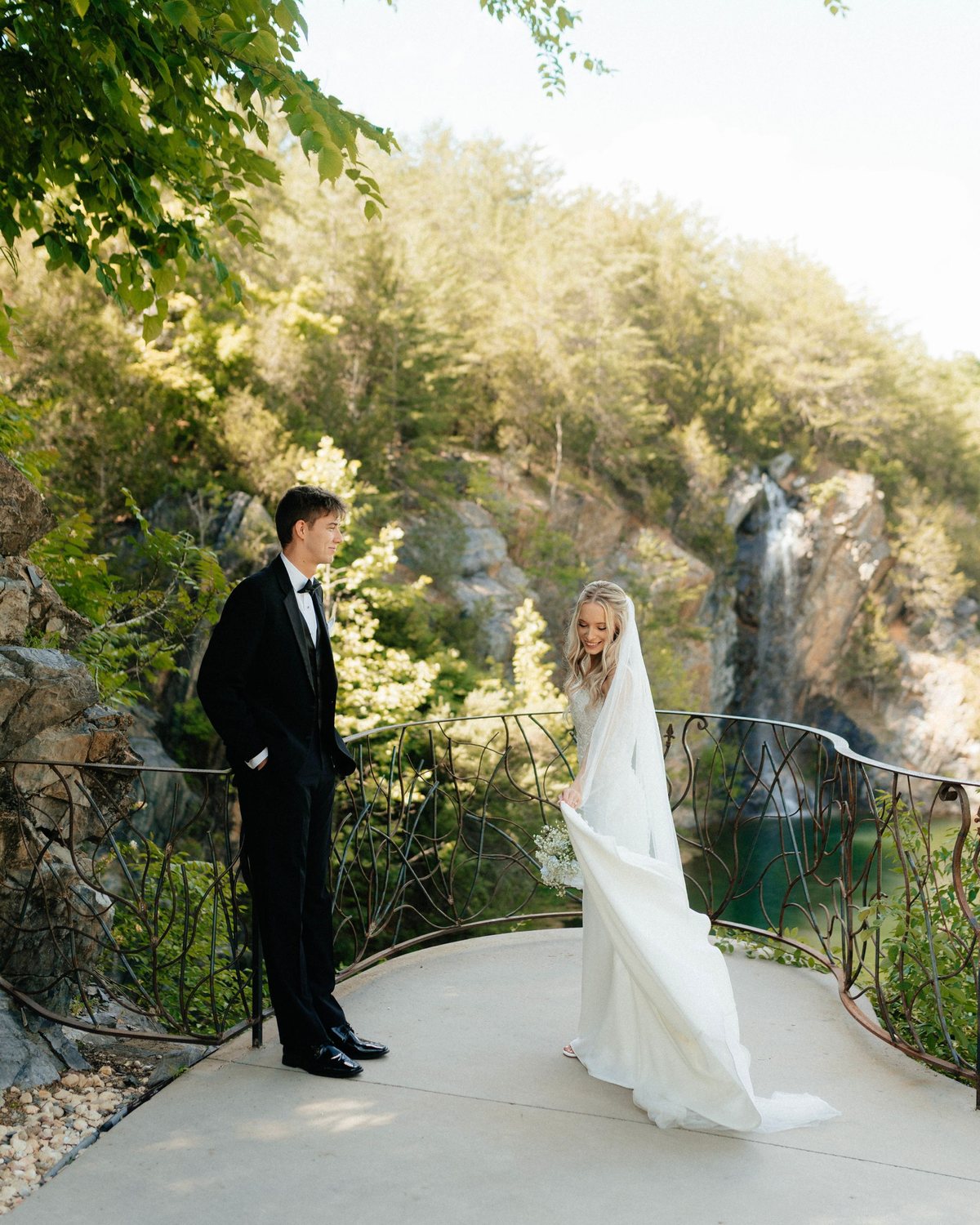 Bride and groom on a curved overlook in front of a waterfall