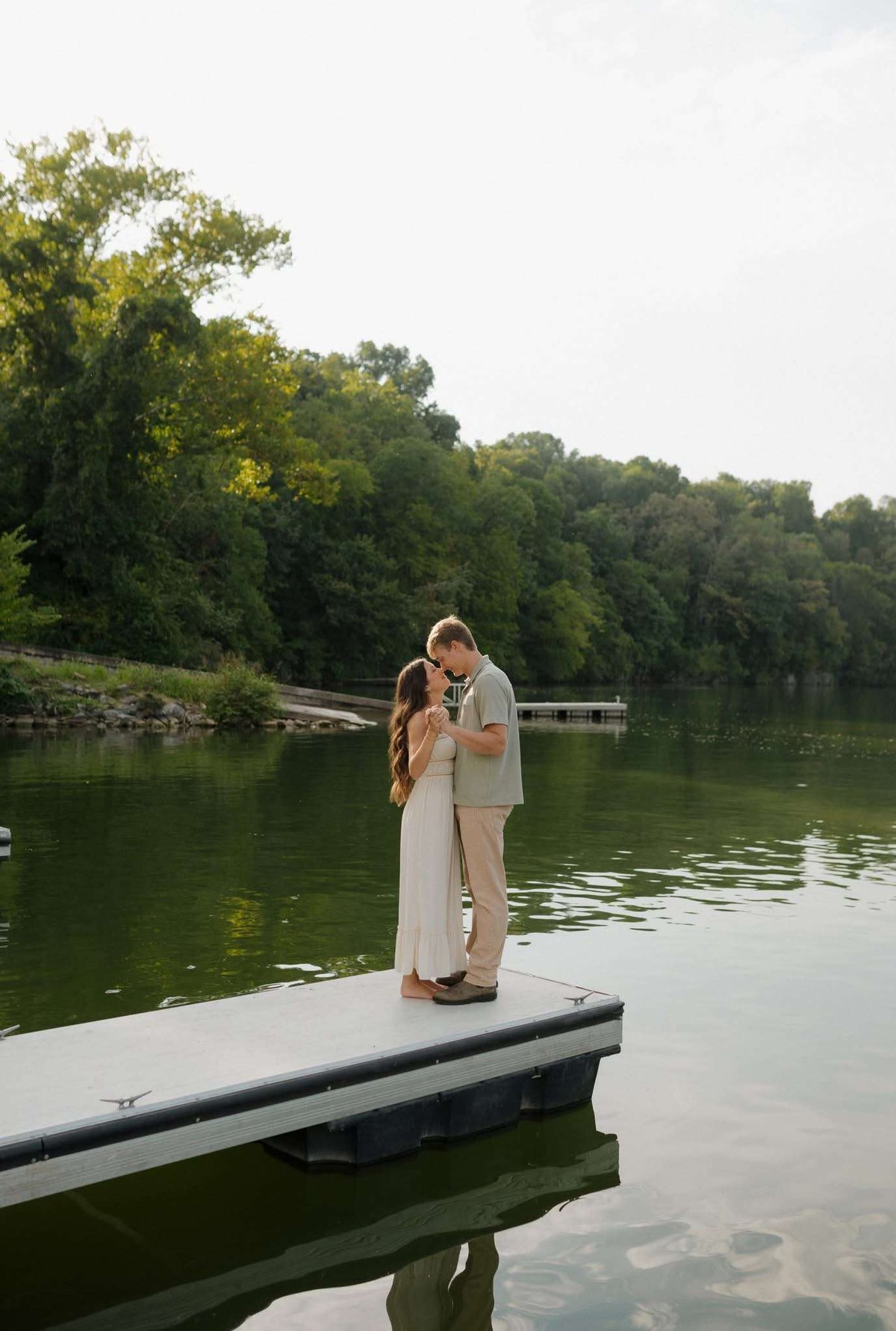 Couple standing forehead to forehead on a dock over a green river